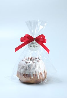 a frosted donut wrapped in cellophane with a red ribbon around it