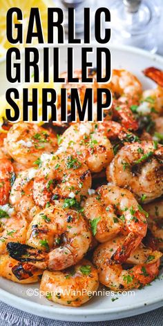 garlic grilled shrimp on a white plate with lemon wedges and parsley garnish