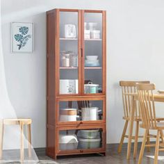 a wooden cabinet with glass doors next to a dining room table