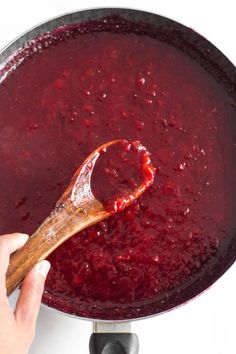 a wooden spoon is being used to stir beet sauce in a pan on the stove