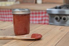 a wooden spoon sitting on top of a table next to a jar filled with ketchup