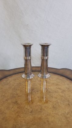 two silver candlesticks sitting on top of a wooden table