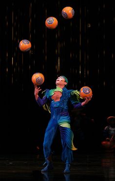 a man juggling balls in the air with his arms and legs spread out to catch them