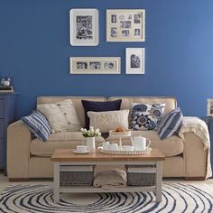 a living room with blue walls and white furniture in the corner, including a coffee table