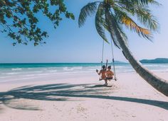 a man sitting on a swing at the beach