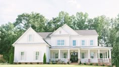 a large white house sitting on top of a lush green field