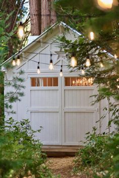 a white shed with lights hanging from it's roof