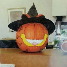 an orange pumpkin with a black hat on it's head sitting on a table