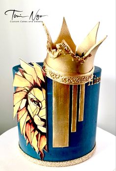 there is a blue and gold cake with a crown on top