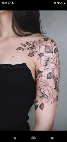 a woman wearing a black dress with flowers on her arm and shoulder tattooing it