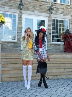 two women dressed in costumes talking on their cell phones while walking up the steps to a house