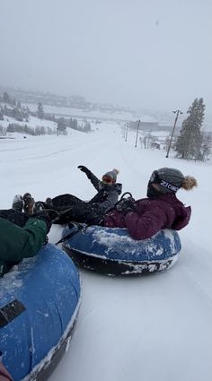 two people are sledding down a snowy hill