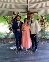 two men and a woman posing for a photo under an umbrella at a wedding ceremony