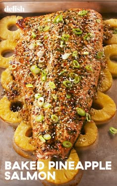 baked pineapple salmon on a baking sheet with sliced pineapples and sesame seeds