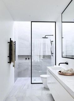 a white bathroom with two sinks and a large mirror on the wall next to it