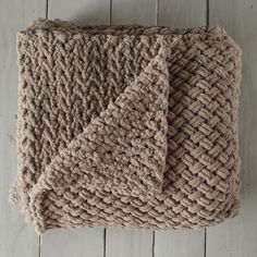 a brown knitted blanket laying on top of a wooden floor