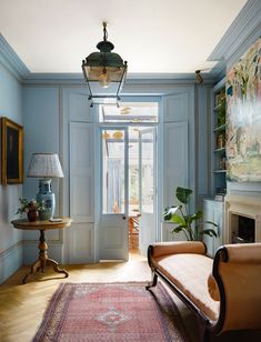 a living room with blue walls and wooden floors is pictured in this image, there are two chairs on either side of the door