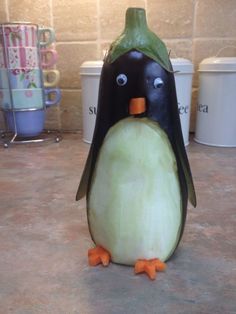 an eggplant shaped like a penguin sitting on top of a counter next to cups