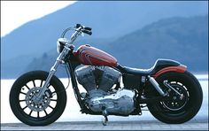 a red and black motorcycle parked next to a body of water