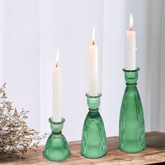 three green glass vases sitting on top of a wooden table