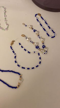 several beaded necklaces are displayed on a white table with a mirror in the background