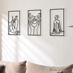 three black and white line art prints hang on the wall above a couch in a living room