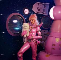 a barbie doll holding a cat in front of a space station