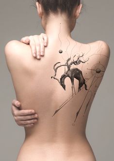 the back of a woman's body with tattoos on it