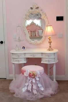 a white dressing table with a mirror on it and a pink stool in front of it