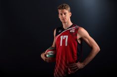 a basketball player holding a ball in his right hand and posing for a photo on a black background