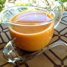 a glass bowl filled with sauce sitting on top of a table next to a spoon