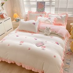 a bedroom with pink and white bedding, teddy bear pillowcases and pillows