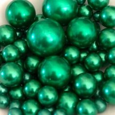 some green balls are in a white bowl on the table and it looks like they have been coated with metallic flecks