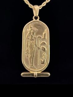 an egyptian gold pendant with the image of pharaoh and his son, on a black background