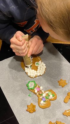 a young boy is making gingerbreads with marshmallows and graham crackers