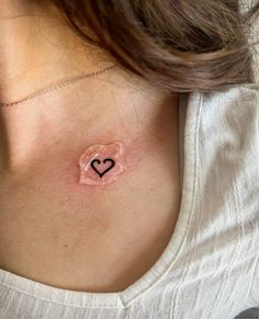 a woman's chest with a heart tattoo on the left side of her chest