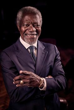 an older man in a suit and tie is posing for a photo with his arms crossed