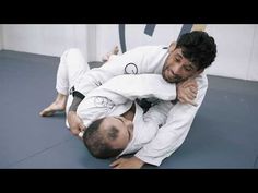 a man in white jacket and black belt doing a kick on another man's head