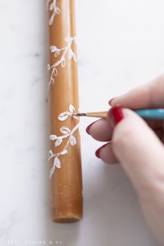 a woman is holding a pencil and writing on a piece of paper with white flowers