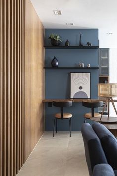 a living room filled with furniture next to a blue wall and wooden slatted walls