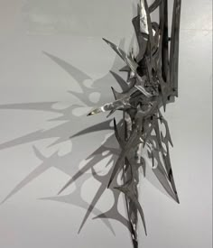 a sculpture made out of metal blades on a white surface with shadows coming from it