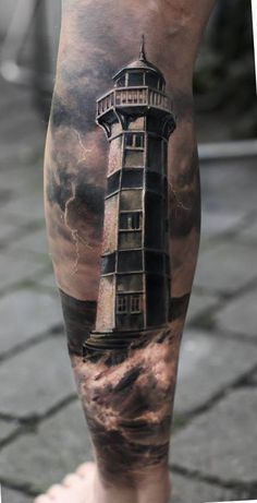 a man's leg with a lighthouse tattoo on it and clouds in the background