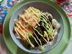 a green plate topped with rice and broccoli covered in sauce