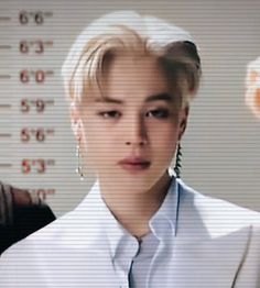 a woman with blonde hair wearing a white shirt and tie in front of a wall