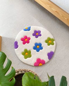 a white rug with colorful flowers on it next to a potted plant and a bed