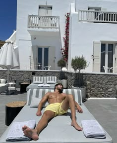 a man laying on top of a bed in front of a building with white balconies