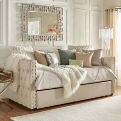 a living room filled with furniture and a large mirror on the wall above it's headboard