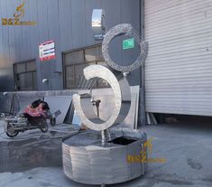 a large metal number sitting in front of a building with a motorcycle parked next to it