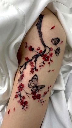 a woman's arm with red flowers and butterflies on it, while she is laying down