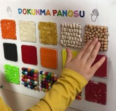 a young child is playing with some colorful beads on a wall mounted display in front of her